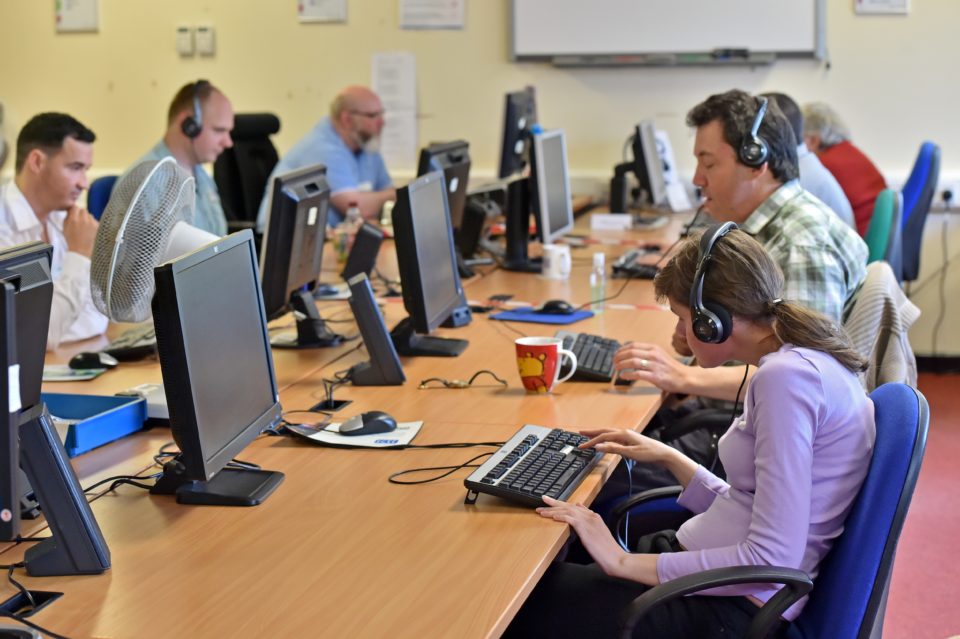 The Shaw Trust Accessibility Services testing team are sat within an office in front of desktop computers, all assessing varying websites to see if they are inclusive.