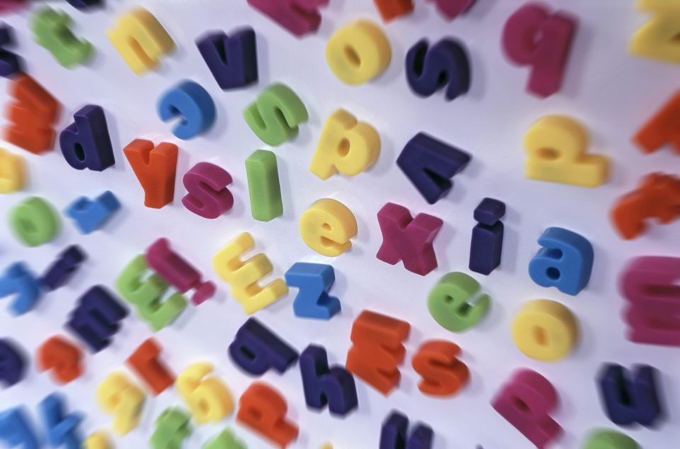 Jumbled blurred lettering as seen by a person suffering from dyslexia with the word DYSLEXIA scattered through the centre in a conceptual image of this medical disability